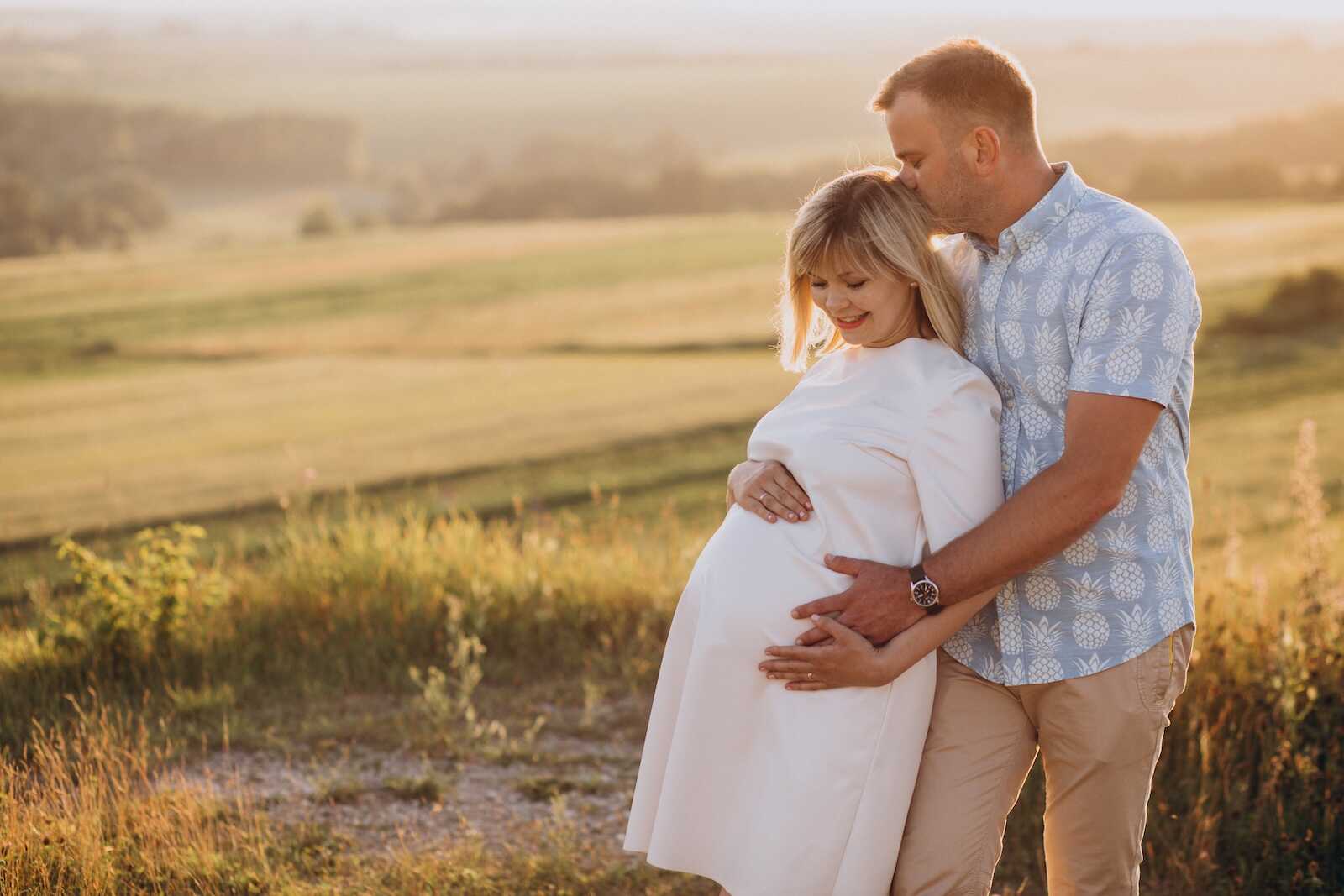 Couple embracing during sunset maternity session showing the best time to take maternity photos.