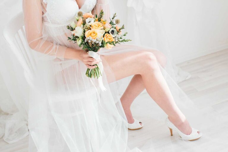 Bride in sheer robe holding bouquet during a bridal boudoir session for bridal boudoir gifts.