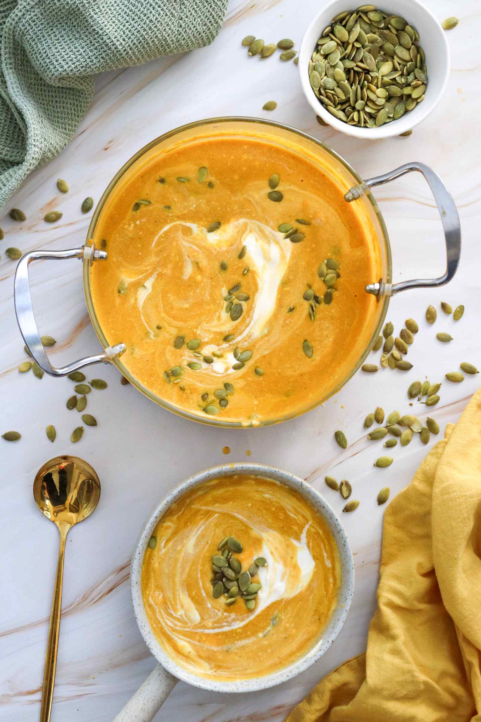 Creamy pumpkin soup topped with pumpkin seeds and cream.