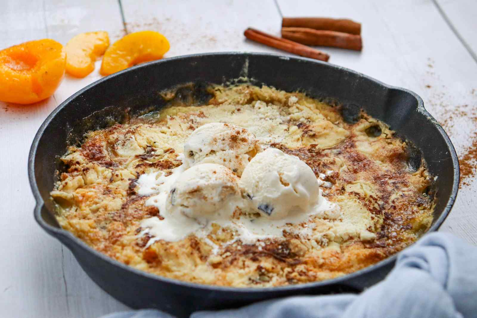 Freshly baked Skillet Peach Dump Cake in a cast iron skillet topped with vanilla ice cream.